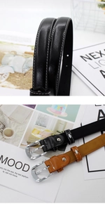 Detail view of black and brown leather belts featuring white contrast stitching and silver buckle
