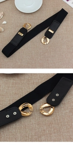Close-up of golden metal interlocking buckle on black elastic waist belt for dresses