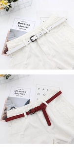 Close-up of white and burgundy thin leather belts styled on distressed denim shorts