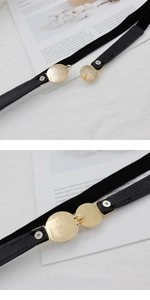 Détail de la ceinture élastique noire avec boucle dorée ronde et fermoir crochet