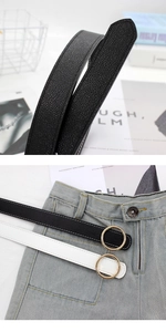 Détail de la boucle ronde dorée et du cuir texturé sur des ceintures noir et blanc