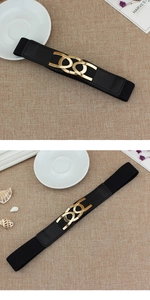 Detail of black elastic belt for women featuring interlocking gold metal buckle