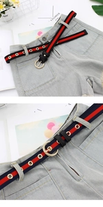 Détail de ceintures en toile rayée avec boucles rondes dorées sur un jean