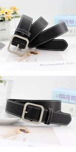 Détail de la ceinture en cuir noir avec boucle rectangulaire argentée et couture blanche