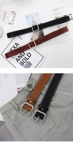 Détail de ceintures en cuir noir et marron avec surpiqûres blanches et boucle carrée