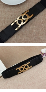 Close-up of interlocking gold geometric buckle on a black elastic women's fashion waist belt