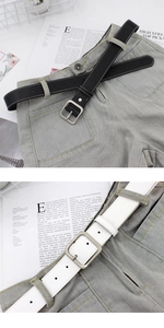 Détail de fines ceintures noires et blanches avec boucles carrées sur un jean gris