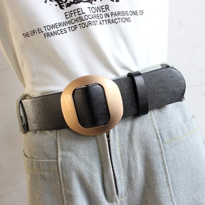 Ceinture femme en cuir noir avec boucle ovale dorée mate sur un jean bleu clair