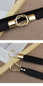 Detail of black elastic waist belt featuring an interlocking gold metal buckle closure