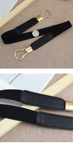Close-up of black elastic waist belt with gold metal hook and lychee leather detail