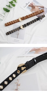 Detail of slim black and brown belts with metal oval grommets and golden buckles