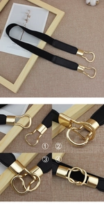 Detail view of elastic black waist belt with gold interlocking metal buckle closure