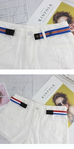 Detail of adjustable elastic no-buckle belts on white distressed denim shorts