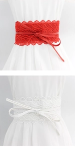 Macro detail of wide lace corset belt in red and white with synthetic leather strap