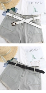 Close-up of high-waist denim shorts featuring raw frayed hems and square buckle PU belts