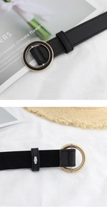Detailed macro view of black PU leather belt with golden metal round buckle front and back