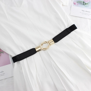 Elastic black skinny belt with gold interlocking rings on a white dress