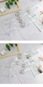 Dettaglio di cinture in PVC trasparente con fibbie in argento a cuore e tonde