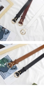 Detailed close-up of slim leather belts with gold round buckles and contrast stitching