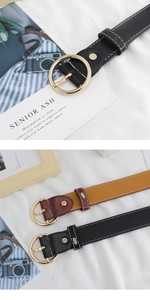 Detail of vintage round gold buckle on leather belts with contrast white stitching