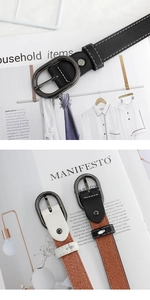 Détail d'une ceinture fine en cuir avec boucle ovale en métal et surpiqûres blanches