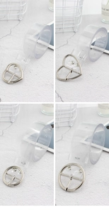 Dettaglio di cinture in PVC trasparente con fibbie in metallo argento a cuore e tonde