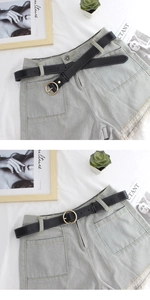 Detail of light blue denim shorts with frayed hems and a black belt with gold circular buckle