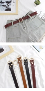 Detail of colorful narrow leather belts with gold round buckles on denim shorts