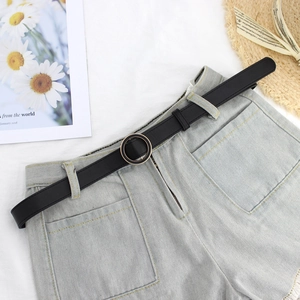Women's minimalist black thin belt with golden round buckle on denim shorts