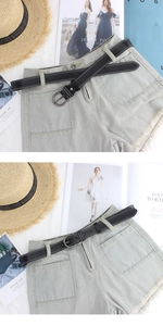 Dettaglio di pantaloncini di jeans azzurri a vita alta con orlo a frange e cintura nera