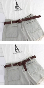 Detail of slim brown leather belt with oval buckle on light blue denim shorts