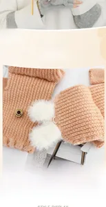 Close-up of winter knitted fingerless gloves with plush rabbit pom-poms and wood button