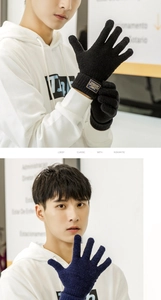 Close-up of men's knitted winter gloves in black and navy with stylish leather patch detail