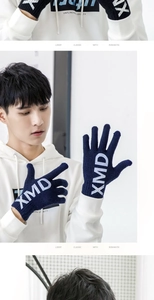 Detail of dark blue knitted touchscreen gloves featuring white XMD letters and elastic cuffs