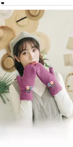 Close-up of purple knit mittens with colorful pom-poms and a cute bow detail