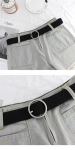 Detail view of denim shorts with round metal buckle belt and yellow contrast stitching