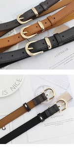 Détails de trois ceintures fines en cuir noir, marron et caramel avec boucles dorées