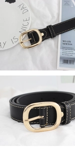 Détail de ceinture en cuir noir avec boucle ovale dorée et coutures blanches contrastées