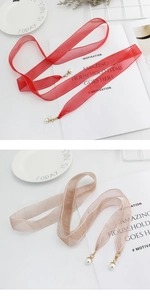 Detail of red and champagne mesh waist ropes with gold clasps and elegant pearl pendants