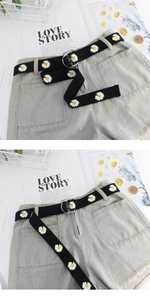 Close-up of black canvas belt with daisy embroidery and double ring buckle on denim