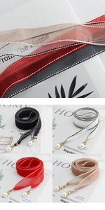 Detail of elegant chiffon waist ribbons with pearl pendants in four distinct colors