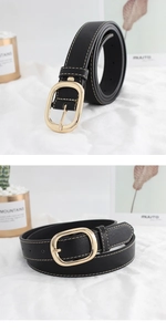 Détail d'une ceinture en cuir noir avec boucle ovale dorée et surpiqûres contrastées