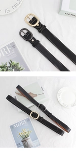 Détail d'une ceinture en cuir noir avec surpiqûres blanches et boucle ovale en métal