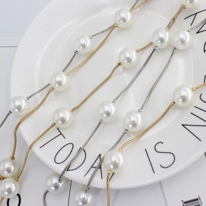 Chaînes de taille fines dorées et argentées avec perles sur un plat décoratif blanc