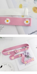 Detail of pink and white canvas belts with daisy embroidery and double D-ring metal buckles