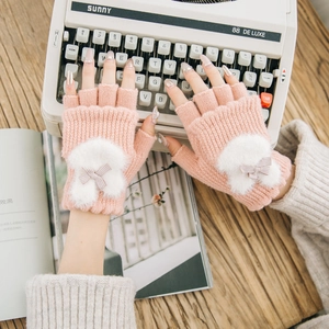 Pink winter knitted fingerless gloves with plush bunny and bow on vintage background