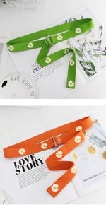 Detail of embroidered daisy pattern and silver double D-ring buckle on canvas belt