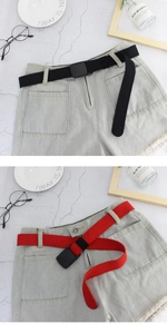 Détail de ceintures en toile rouge et noire avec boucles en plastique sur un short