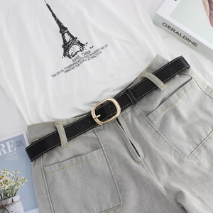 Ceinture chic en cuir noir pour femme avec boucle ovale dorée polie sur un jean bleu