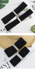 Detail of black elastic waist belt with silver metal interlocking buckle and woven texture